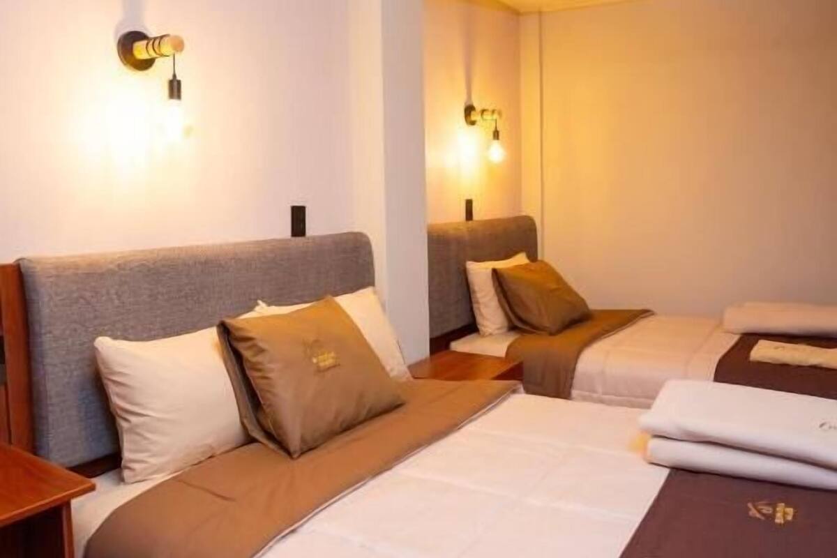 Hotellihuone, jossa on suuri sänky, kaksi yöpöytää ja peili.