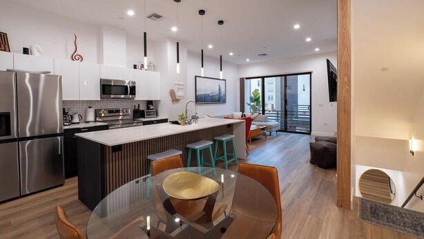 Cozinha moderna com eletrodomésticos de aço inoxidável, ilha central com banquetas e iluminação pendente.