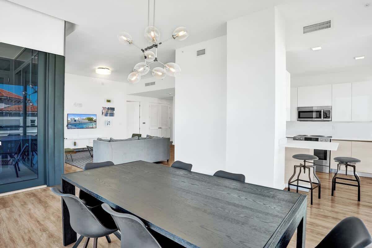 Dining area with gray dining table, bar seating, and open kitchen with white cabinetry