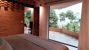 A bedroom with a large bed, a view of a balcony, and a brick wall. - The sea in front of your window! (Puerto Vallarta)