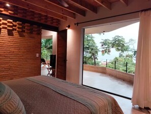 Ein Schlafzimmer mit einem großen Bett, Balkonblick und einer Backsteinwand.