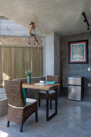 A dining area with wicker chairs, a wooden table, a hanging light fixture, a bamboo screen, and a refrigerator. - Views, sea and jungle - Escape to paradise - (Puerto Vallarta)