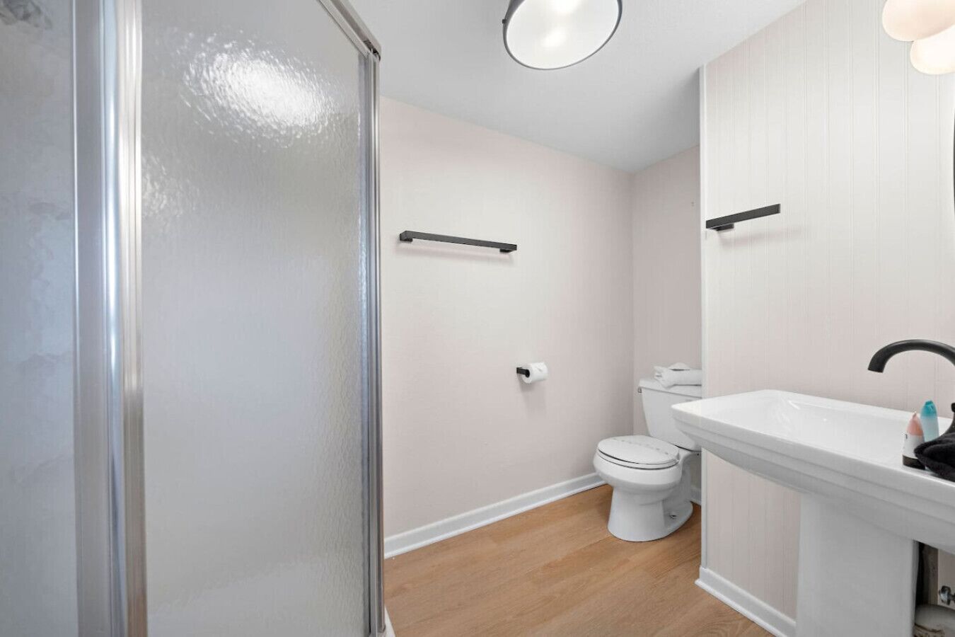 Et badeværelse med brusekabine i glas, toilet og vask med spejl.