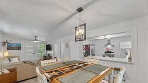 Una sala moderna con comedor, paredes blancas y un ventilador de techo.