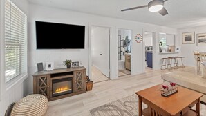Una sala de estar moderna con chimenea, televisor de pantalla plana y ventilador de techo.