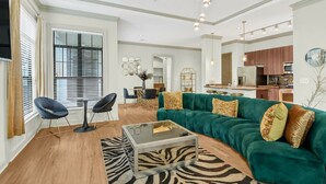 A modern living room with a green sofa, a glass coffee table, and a zebra-patterned rug. - Cozy 2-bedroom condo in serene Atlanta with AC and fitness room (Atlanta)