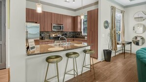 A modern kitchen with a central island, stainless steel appliances, and bar stools. - Cozy 2-bedroom condo in serene Atlanta with AC and fitness room (Atlanta)