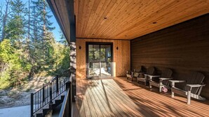 Um deck de madeira com área de estar externa e porta de vidro que dá para um terraço.