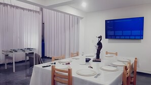 Ein Essbereich mit einem langen Tisch, der für eine Mahlzeit gedeckt ist, weißen Vorhängen und einer blauen Wandfläche.