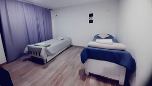 Ein kleines, sauberes Zimmer mit zwei Einzelbetten, Holzboden und schlichtem Design.