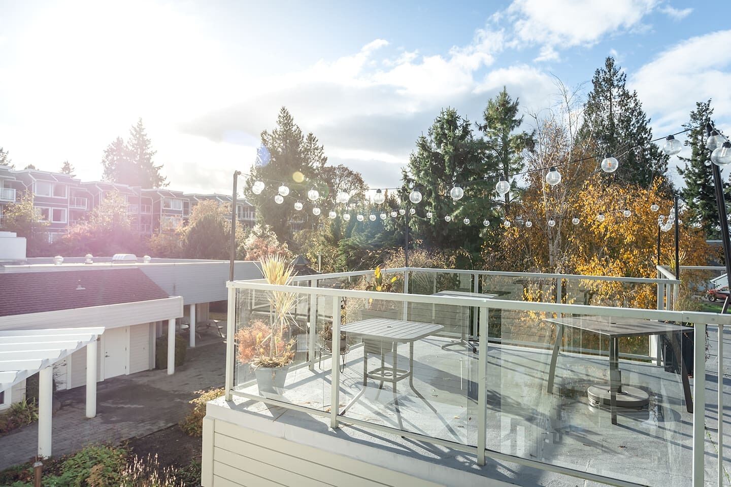 Una terrazza sul tetto con ringhiera in vetro, arredi da esterno e luci decorative.