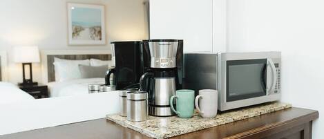 Eine Küchenzeile mit Kaffeemaschine, Mikrowelle und zwei Tassen auf einer Arbeitsfläche.