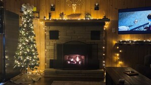Ein gemütliches Wohnzimmer mit Kamin, Weihnachtsbaum und Fernseher.