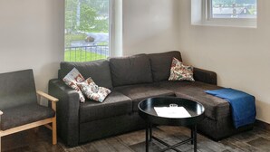 Un salon moderne avec un canapé d’angle, une petite table ronde et un fauteuil.