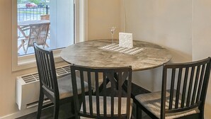 Une table ronde surmontée d’un plateau en marbre, entourée de quatre chaises en bois foncé dotées d’assises rembourrées. Un objet décoratif à motifs géométriques est posé sur la table.