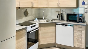 Une cuisine compacte avec des meubles en bois, un lave-vaisselle encastré, une cuisinière et un four à micro-ondes.
