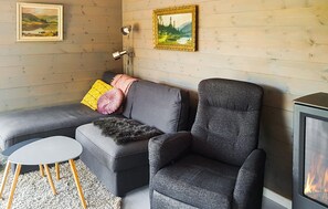 Ett mysigt vardagsrum med en grå soffa, en tillhörande fåtölj, ett litet bord och en öppen spis.