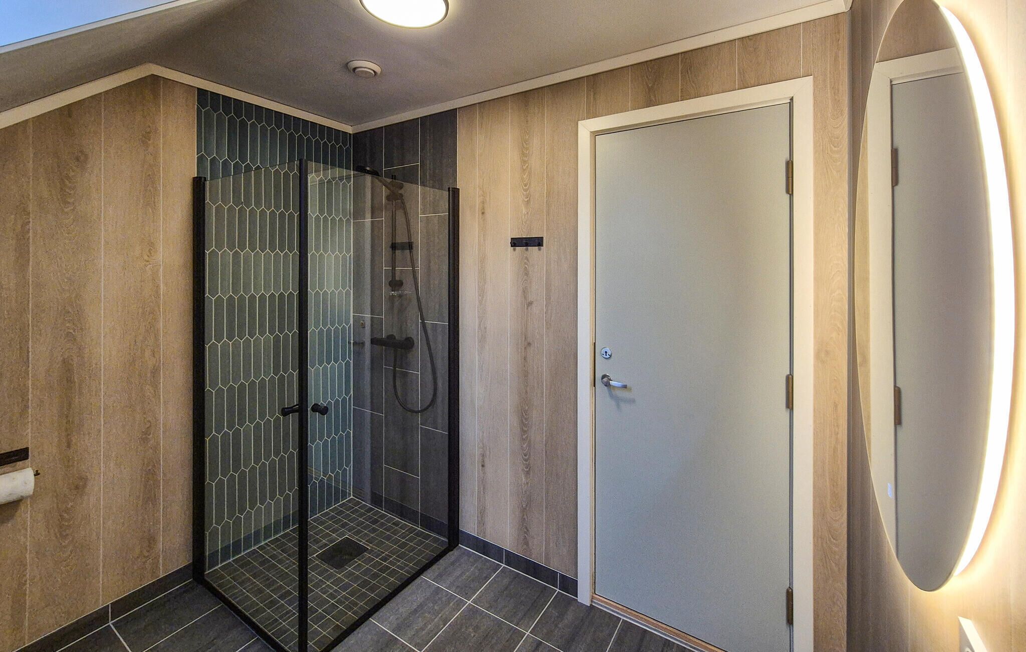 Ein modernes Badezimmer mit einer Duschkabine aus Glas, einem Holzbadezimmer-Möbel und einer spiegelnden Tür.