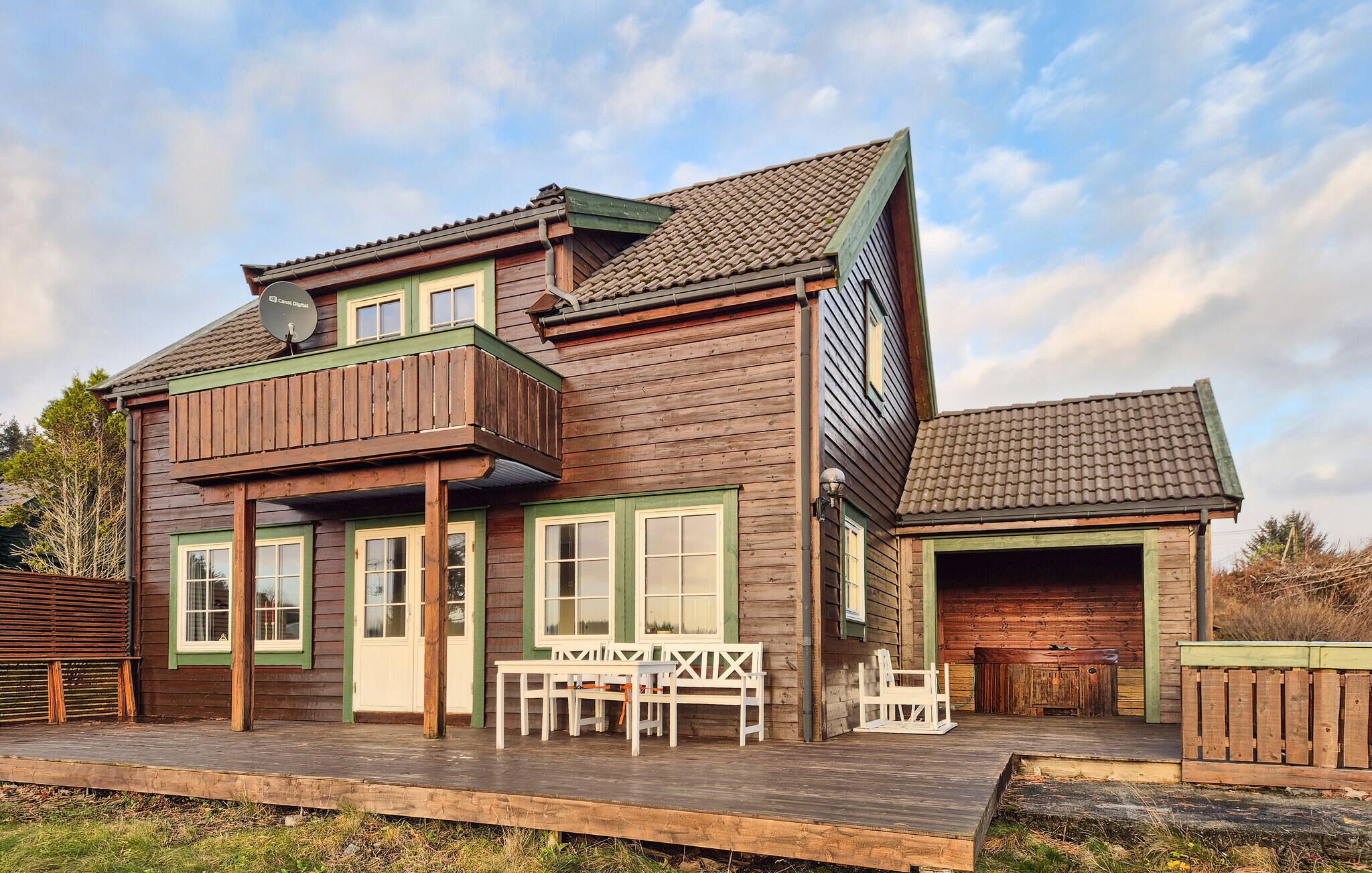 A two-story wooden house with a balcony, a covered porch, and a garage.