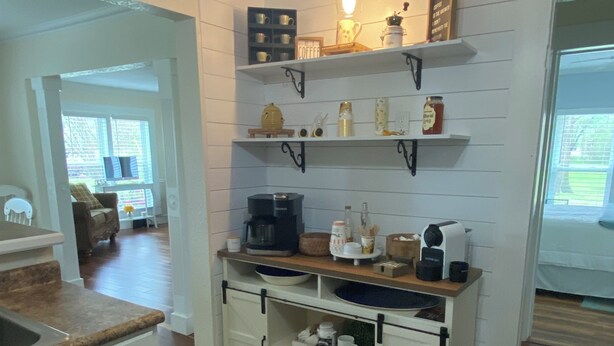Una cocina con armarios blancos, una zona para café y vistas al salón.