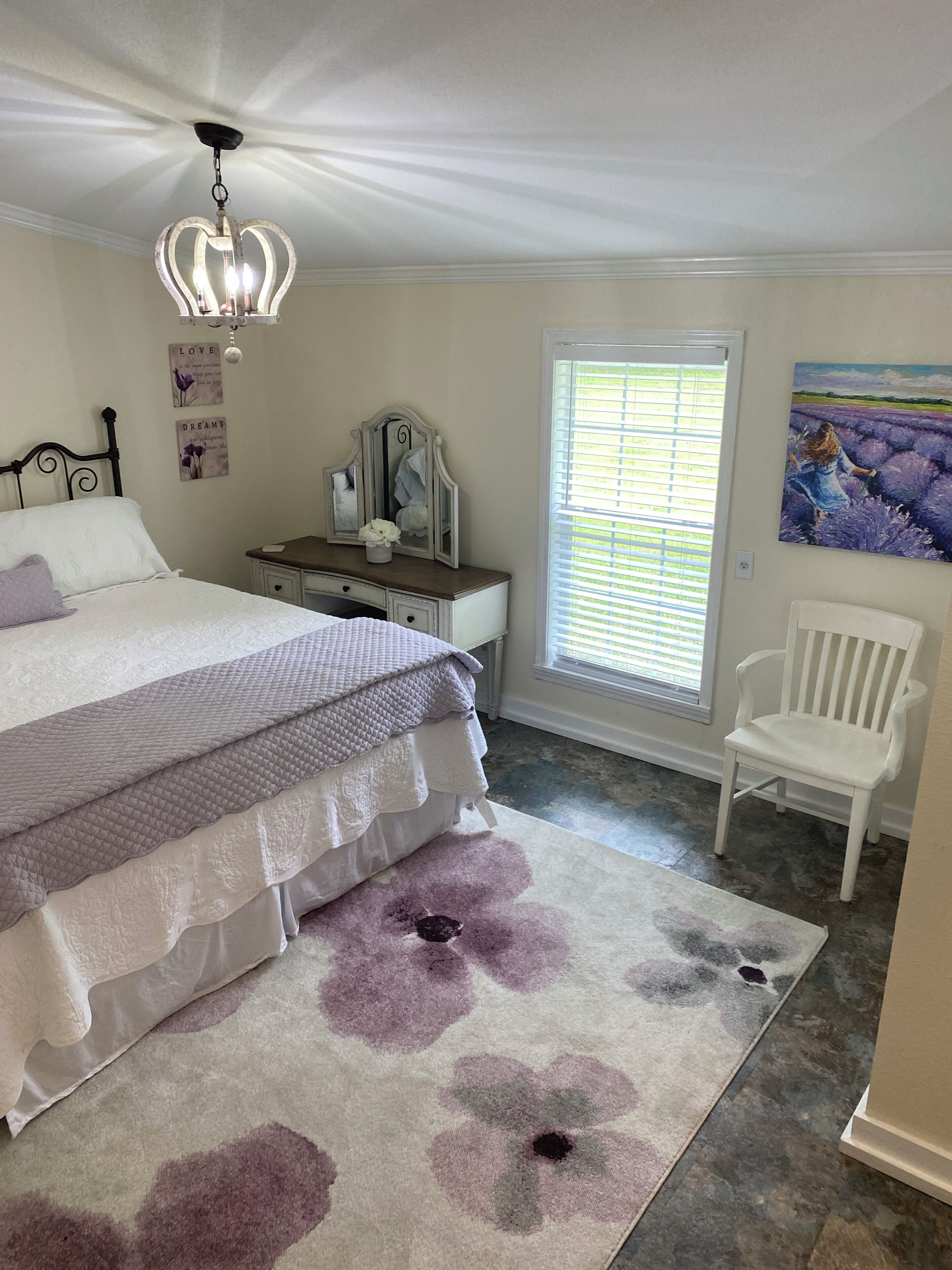 Ein Schlafzimmer mit Bett, Schminktisch, Stuhl und Kunstwerken.