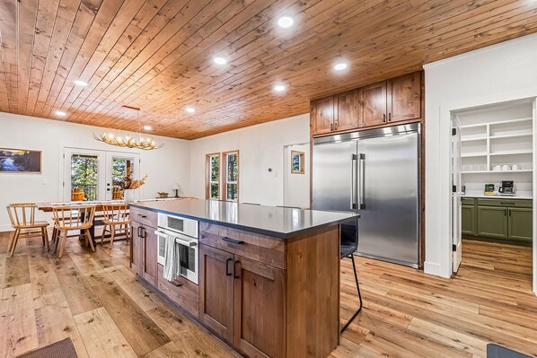 A modern kitchen with wooden cabinetry, a stainless steel refrigerator, and a large island with a sink.
