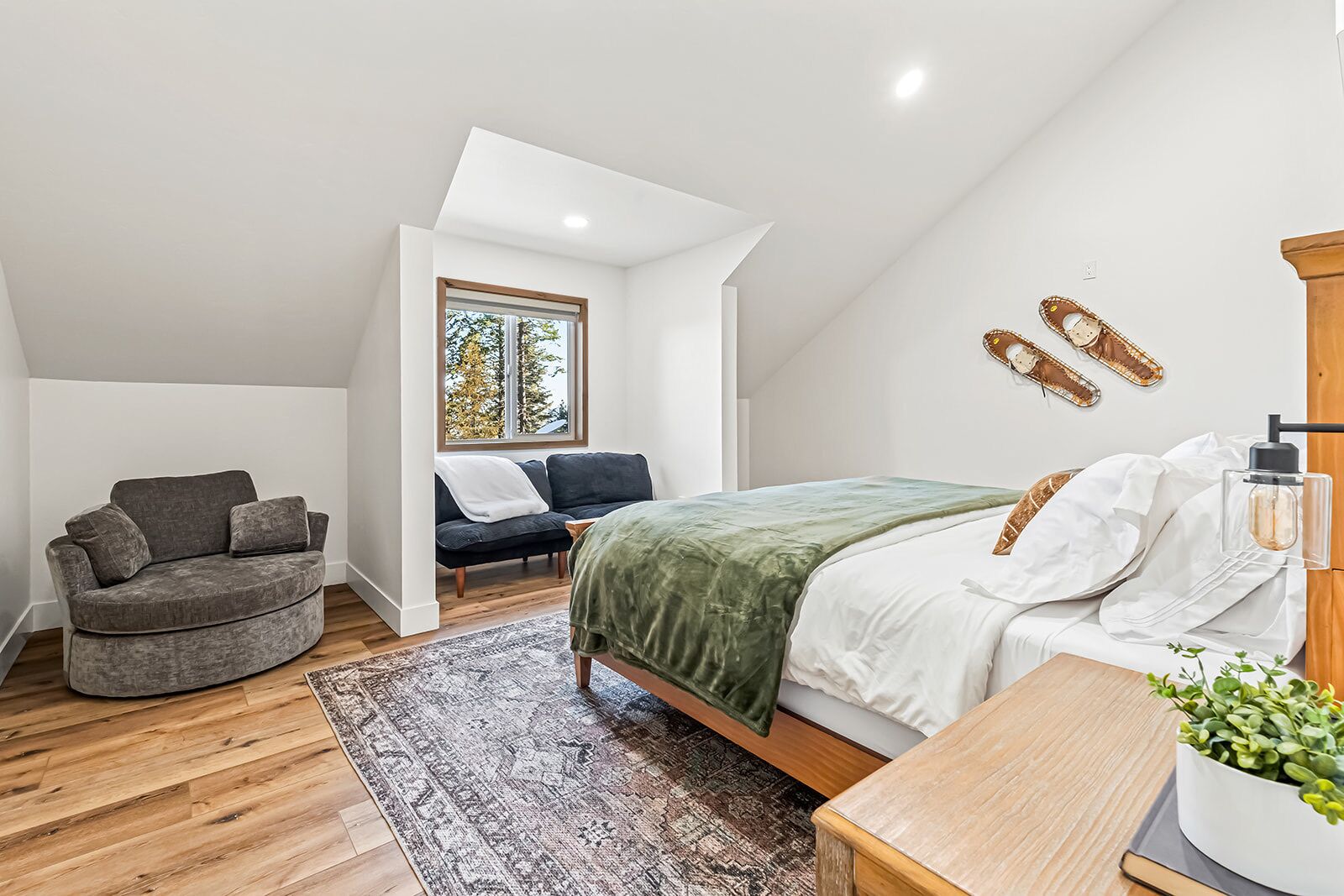 Ein Schlafzimmer mit Bett, Sofa, Fenster und einer Pflanze.