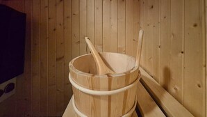 Uma sauna de madeira com um balde e dois bastões de madeira.