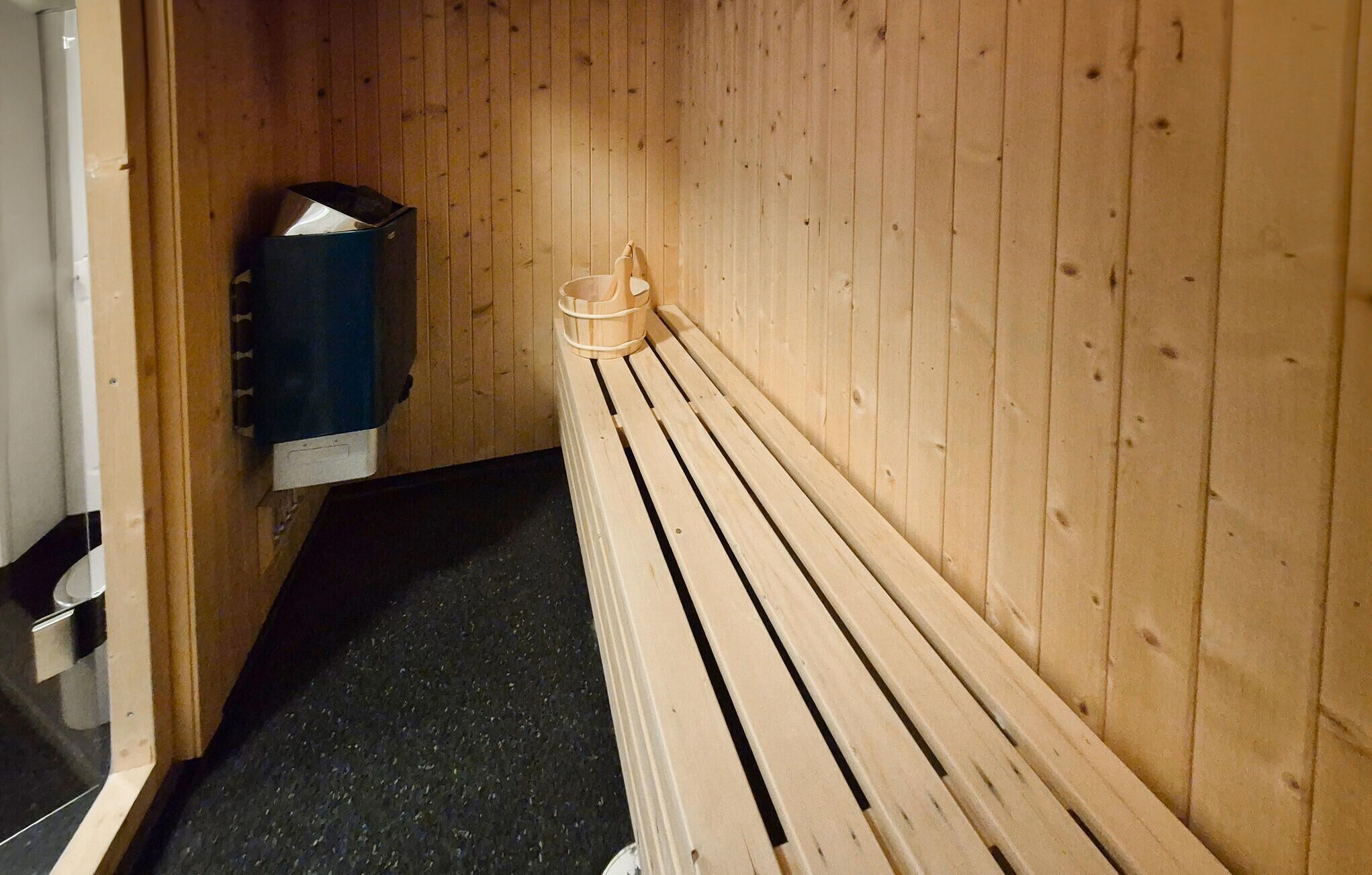 A wooden sauna with benches and a sauna heater.