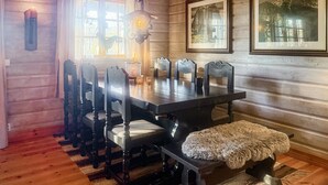 Un comedor con una mesa y sillas de madera, una lámpara colgante y cuadros en la pared.