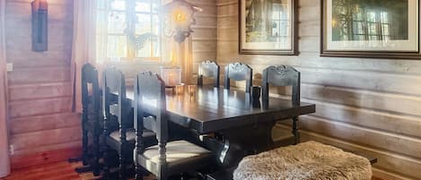 Un comedor con una mesa y sillas de madera, una lámpara colgante y cuadros en la pared.