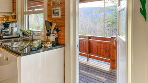 A kitchen with a sink, coffee maker, and a window overlooking a deck.