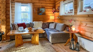 A cozy cabin interior with a wooden interior, a sofa, a table with fruit, and a lamp.