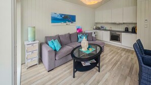 Un soggiorno moderno con un divano grigio, un tavolino da caffè rotondo in vetro e un quadro raffigurante una spiaggia.