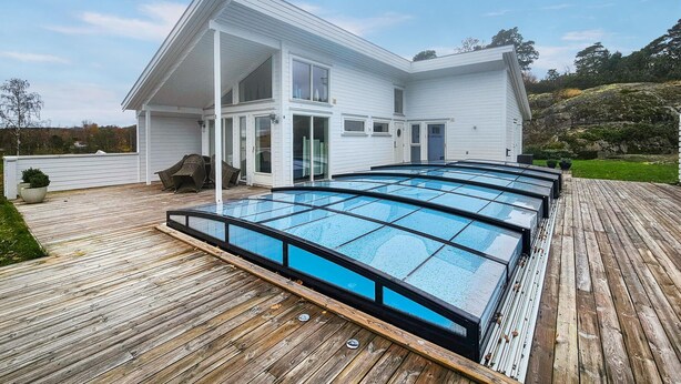 Una casa moderna con una piscina grande, vetrata, su un molo di legno.