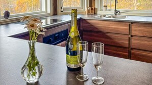 A kitchen counter with a bottle of Prosecco, two wine glasses, and a vase with flowers. - Stunning home in Røros with sauna (Røros)
