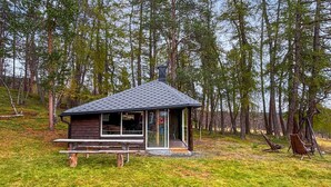 A small cabin with a sloped roof, a wooden deck, and a picnic table. - Stunning home in Røros with sauna (Røros)