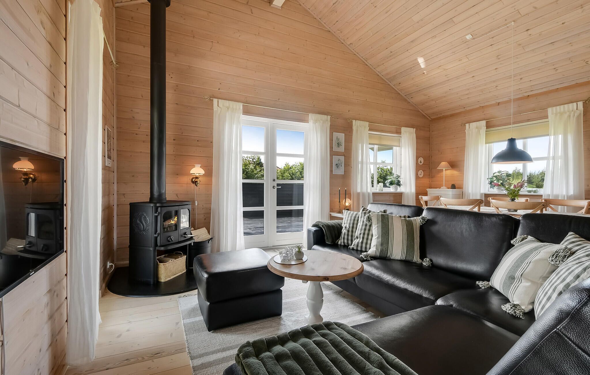 A cozy cabin interior with a fireplace, leather sofa, and a dining area.