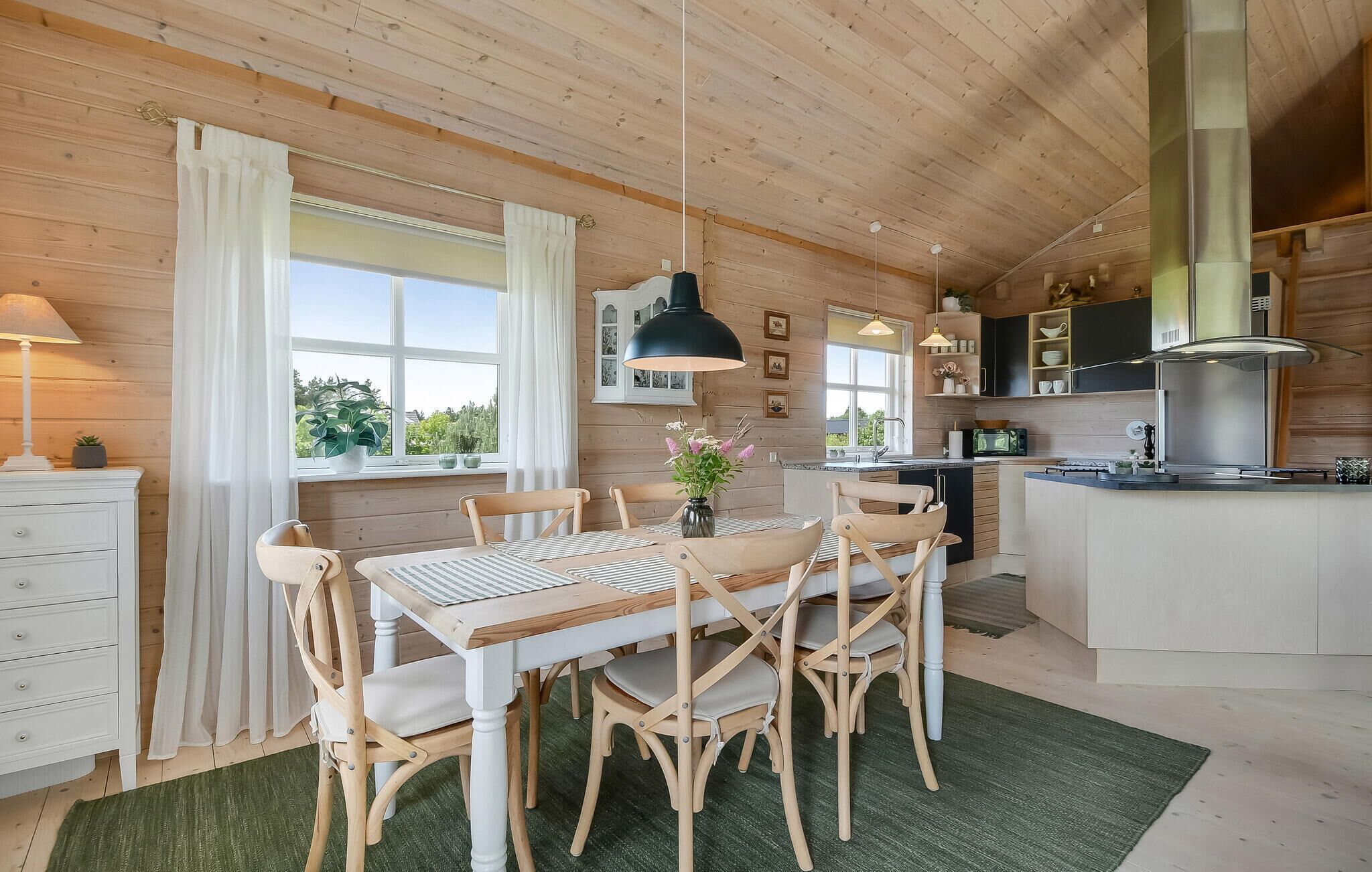 A cozy cabin-style kitchen with wooden walls and a dining area featuring a table and chairs.