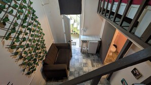 A compact living space with a brown sofa, a small kitchen area, and a staircase. - LA ESPAÑOLA GUESTHOUSE 1 (Santo Domingo)
