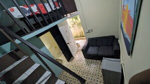 A staircase leading to a room with a black sofa, patterned floor tiles, and a door leading outside. - LA ESPAÑOLA GUESTHOUSE 1 (Santo Domingo)