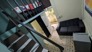 A staircase with a patterned floor, a sofa, and a small table in a room with a door leading outside. - LA ESPAÑOLA GUESTHOUSE 1 (Santo Domingo)