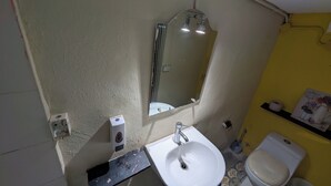 A bathroom with a white sink, a mirror, a shower, and a toilet. - LA ESPAÑOLA GUESTHOUSE 1 (Santo Domingo)
