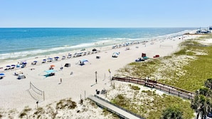 A beach with umbrellas, a volleyball net, and a wooden walkway. - 5 Star Beach Penthouse On Top Floor! Private Elevator & Extra Large Balcony (Gulf Shores)