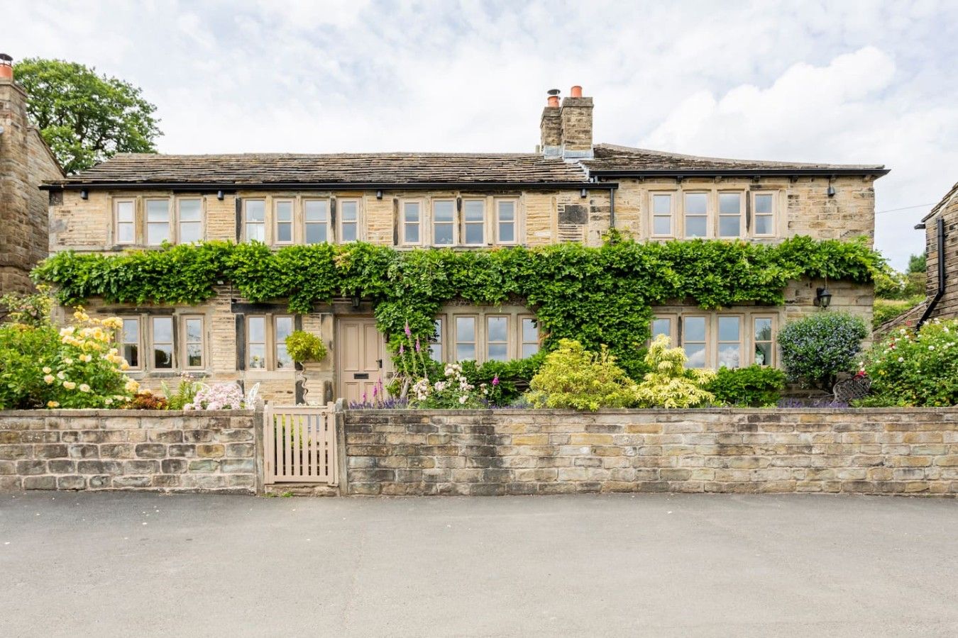 A stone building with a row of windows, a gated entrance, and a stone wall.