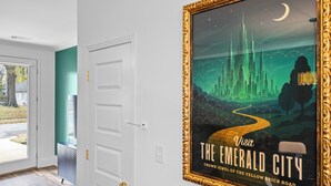 A hallway with a door, a framed poster, and a teal wall. - The Emerald-Contemporary Art Deco–Style Townhome (Memphis)