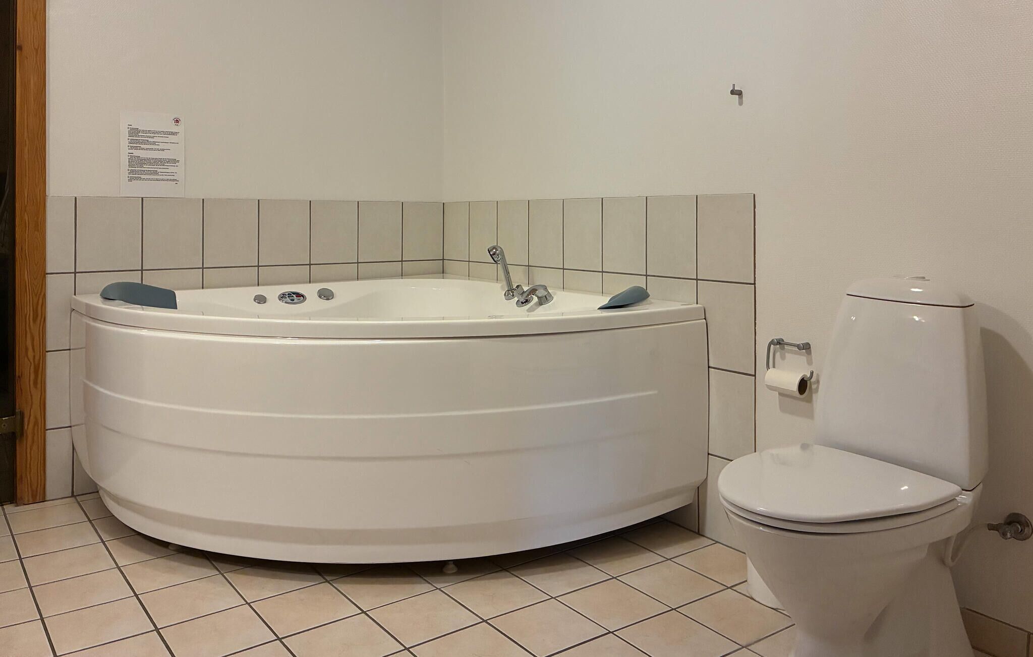 A bathroom with a large bathtub, a toilet, and a tiled floor.
