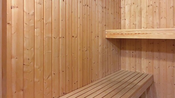 Een sauna met houten wanden en een bank.