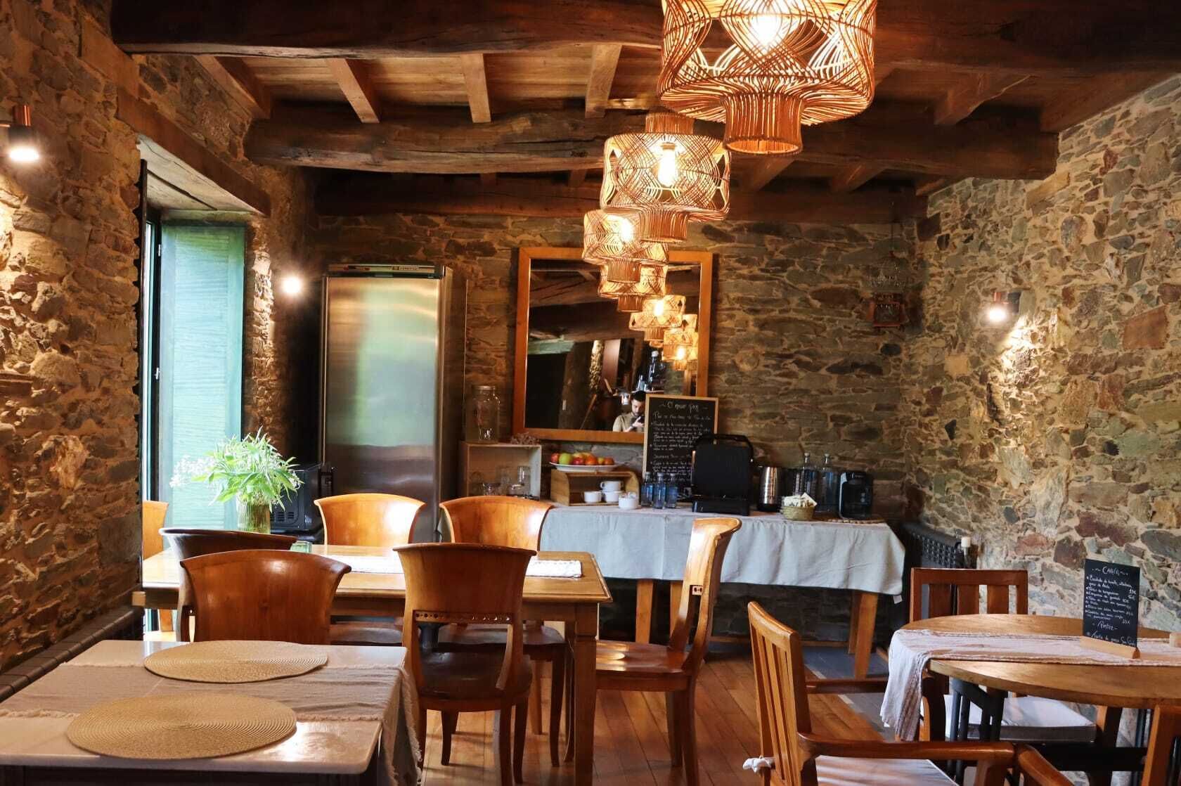 Un interior rústico con paredes de piedra, muebles de madera y lámparas de mimbre colgantes.