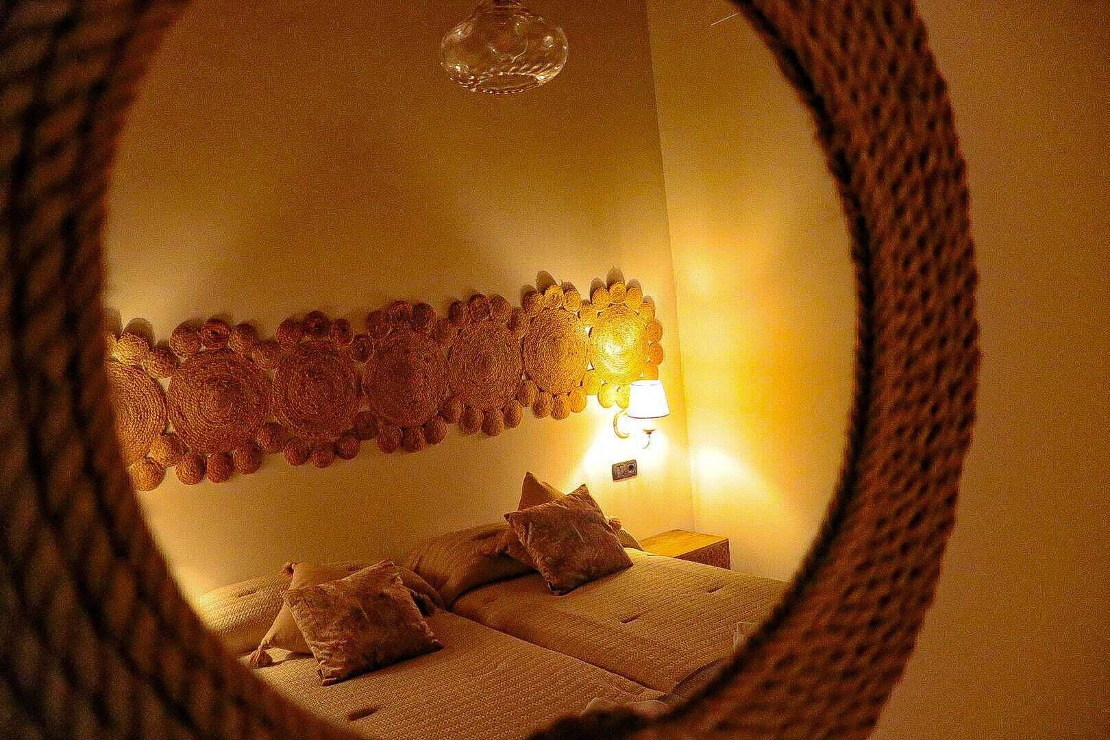 A bedroom with a bed, pillows, a wall-mounted lamp, and a textured wall decoration.